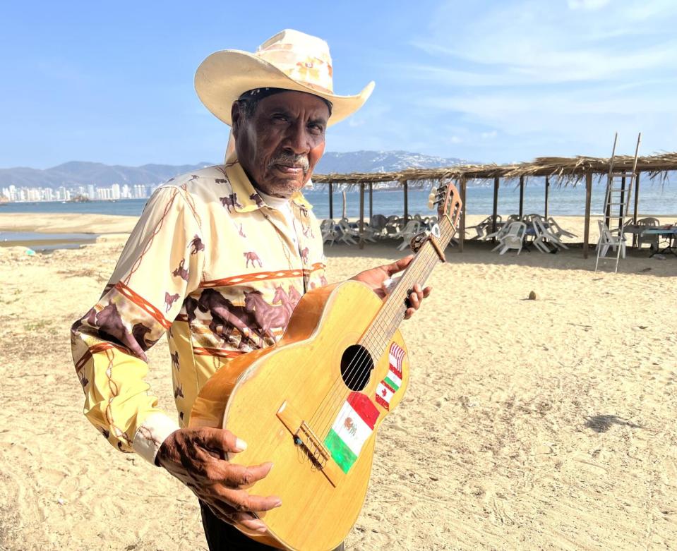 Tomas "El Bronco" Mayo holds his guitar on the beach.