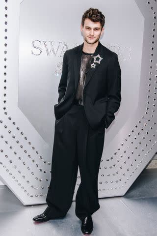 <p> Nina Westervelt/WWD via Getty</p> Brandon Flynn poses in Versace and Swarovski at the grand opening event for the jewelry brand's flagship store on Fifth Ave in NYC