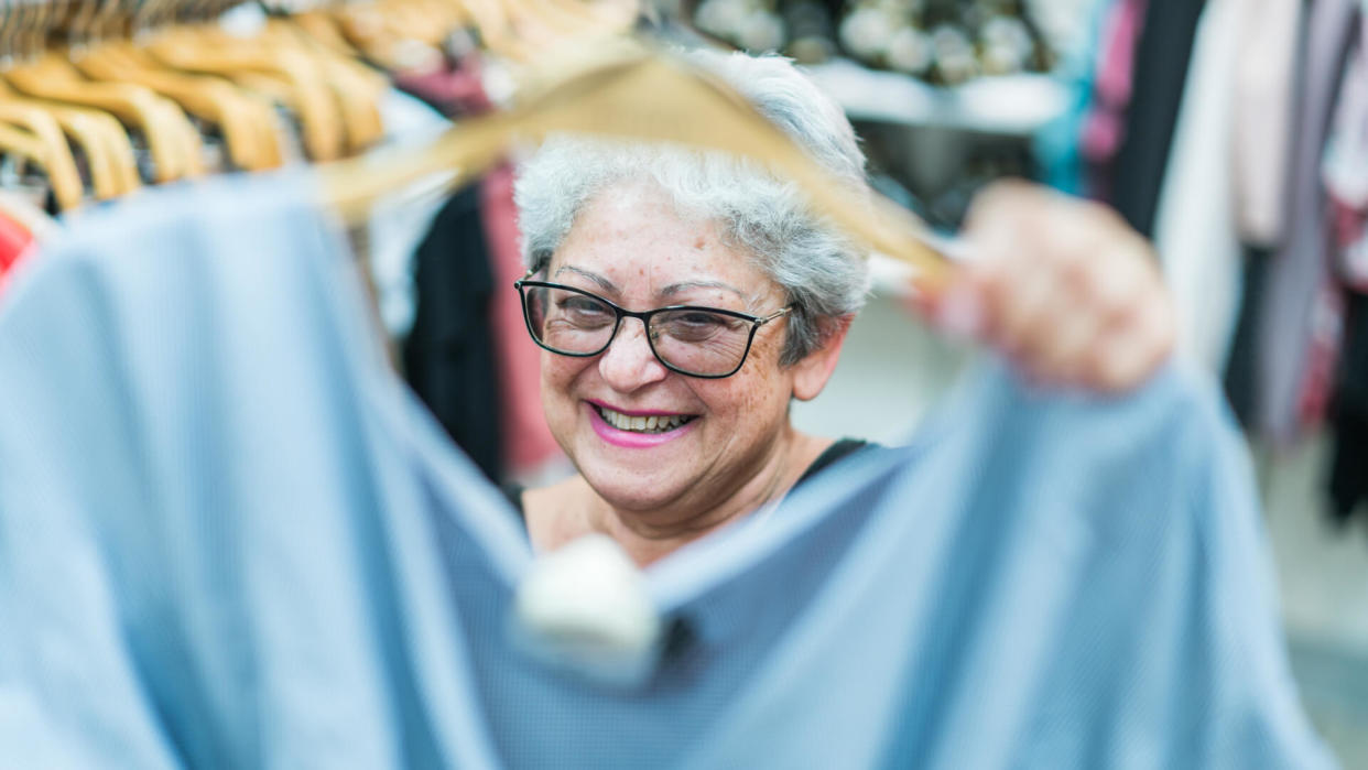 The silver-haired 65-years-old active senior woman shopping in the clothing retail store.