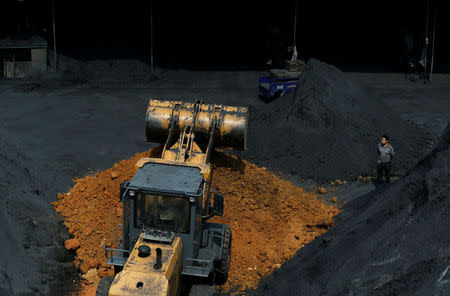 FILE PHOTO: A man stands amidst coal at a factory in Shaoxing, Zhejiang province, April 29, 2014. REUTERS/William Hong/File Photo