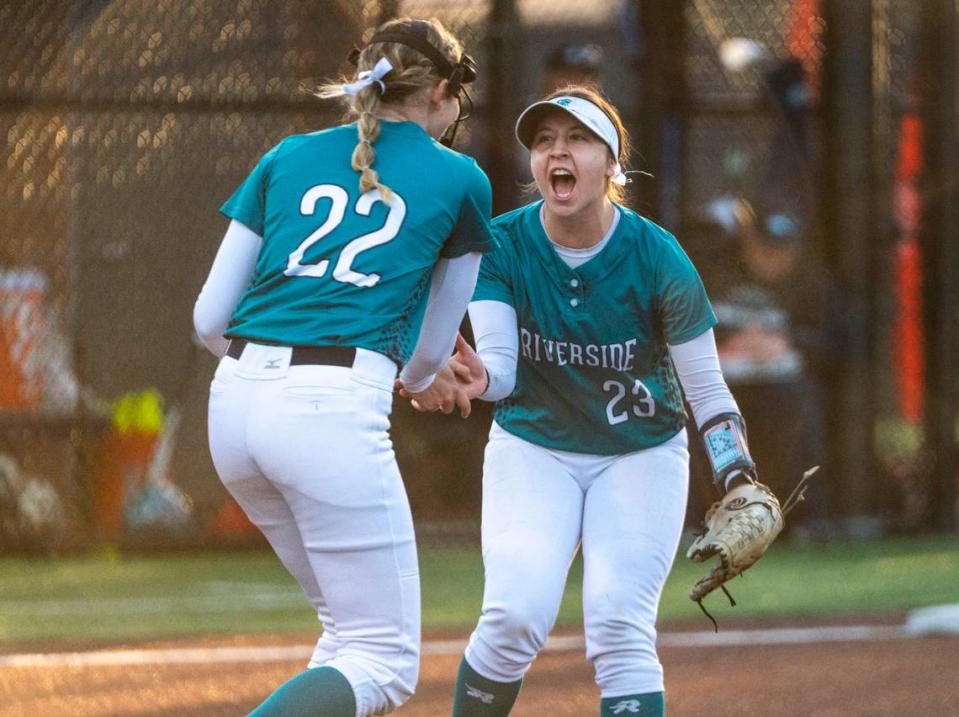 Auburn Riverside Kaylee Walker (23) high-fives Auburn Riverside pitcher Danica Butler (22) after Butler struck out a Kentwood player during a non-conference varsity softball game against Kentwood at Auburn Riverside High School in Auburn, Wash. on April 25, 2023. Kentwood defeated Auburn Riverside 3-0.