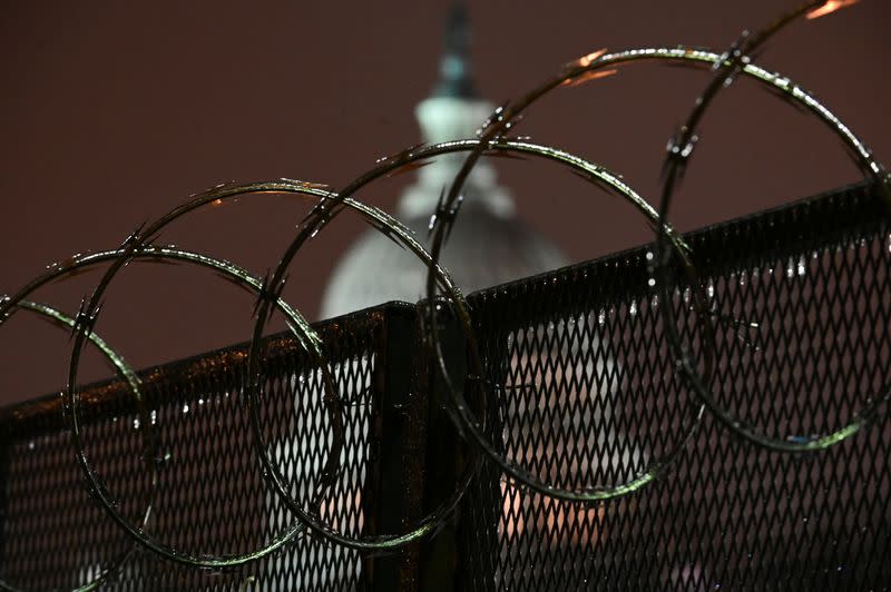 The U.S. Capitol is seen through barbed wire on a security fence after the Senate voted to acquit former U.S. President Donald Trump during his impeachment trial, in Washington