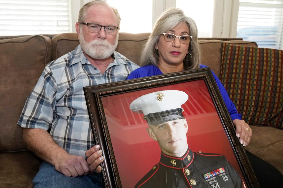 Joey and Paula Reed pose for a photo with a portrait of their son Marine veteran and Russian prisoner Trevor Reed at their home in Fort Worth, Texas, Feb. 15, 2022.