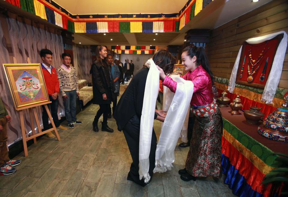 U.S. first lady Michelle Obama (2nd R) receives a traditional prayer scarf from an attendant while daughters Malia (L) and Sasha wait their turn, upon arrival for lunch at the Zangxiang Teahouse in Chengdu, the capital of Sichuan Province, March 26, 2014. (REUTERS/Stephen Shaver/Pool)