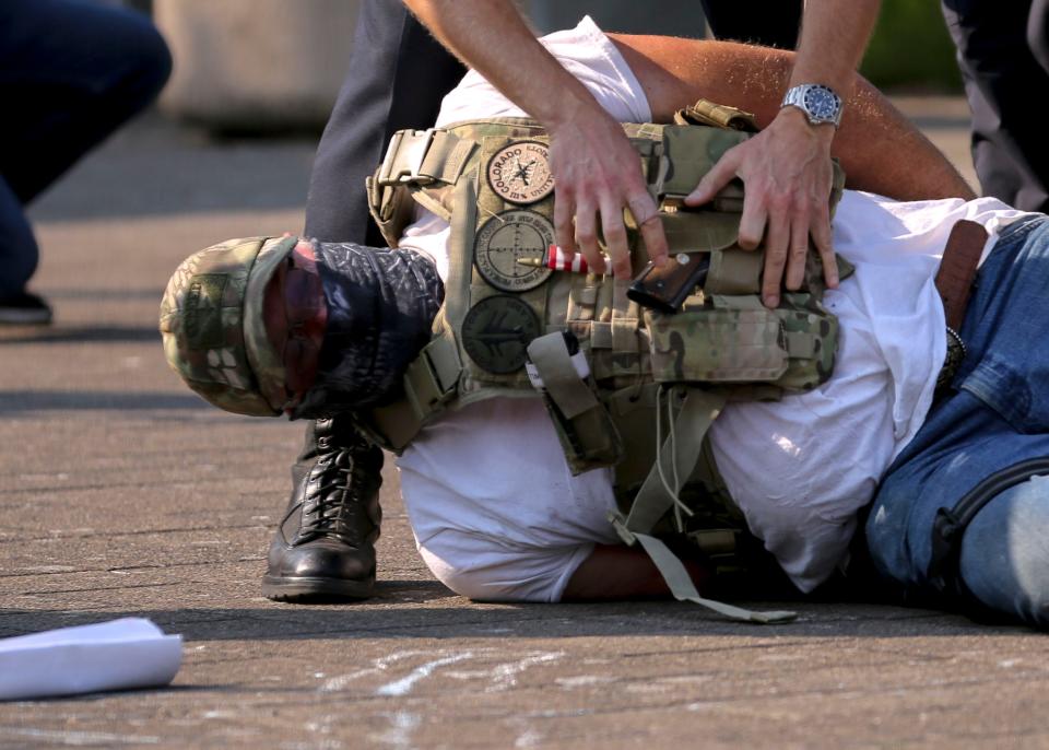 A Salem Police officer removes a gun from the vest of a pro-Trump protester during an American Lives Matter, pro-Trump rally at the Oregon State Capitol in Salem, Oregon on Monday, Sept. 7, 2020. The pro-Trump demonstrator was arrested after assaulting a female Black Lives Matter demonstrator and pushing a cop.