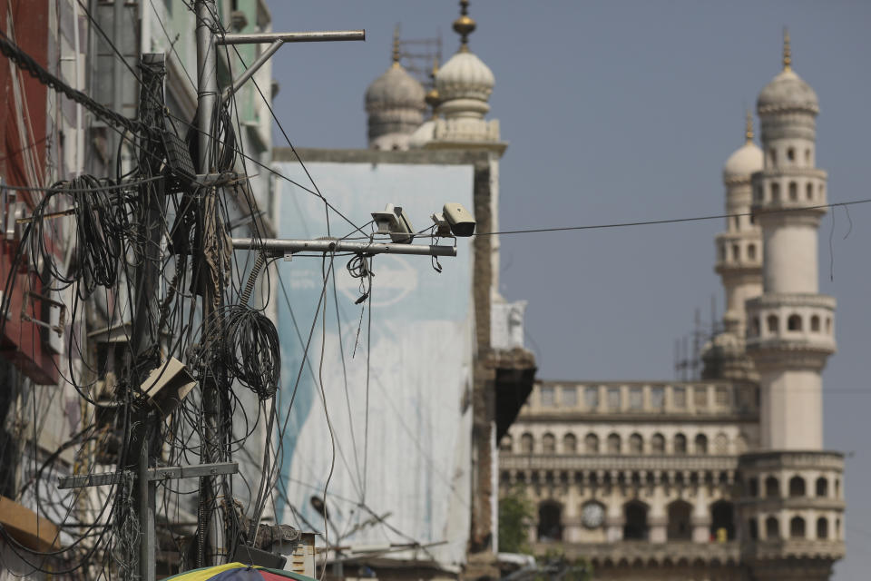 Cámaras de vigilancia colocadas sobre una calle, con el monumento de Charminar al fonbdo, en Hyderabad, India, el viernes 28 de enero de 2022. (AP Foto/Mahesh Kumar A.)