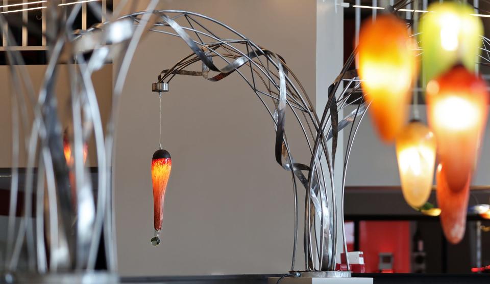 Handblown glass lights from Crave's previous location hang from custom steel cantilevers by John Comunale on Thursday.