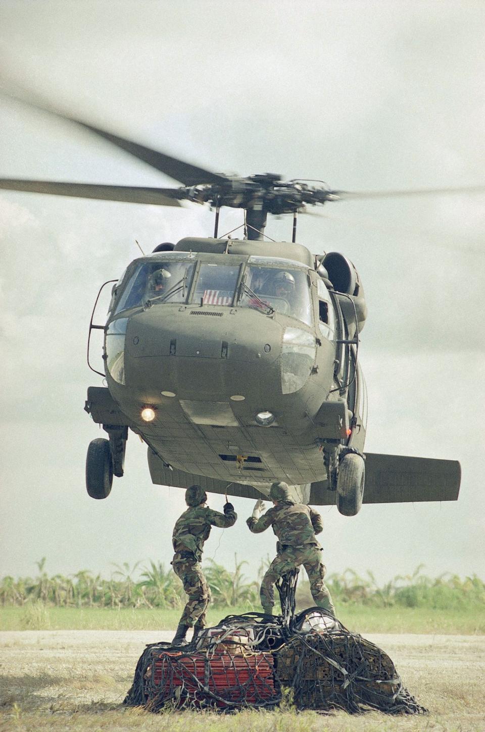 <p>A Blackhawk helicopter hovers over two members of the 49th Quartermaster Detachment from Fort Bragg, N.C., as they attach a sling to it, carrying supplies for victims of Hurricane Andrew, Sept. 11, 1992, at the Homestead Humanitarian Depot. (AP Photo/Kathy Willens) </p>