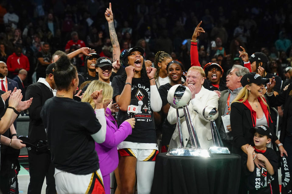 Las Vegas Aces' A'ja Wilson and Mark Davis celebrate with teammates next to the trophy after Game 4 of a WNBA basketball final playoff series against the New York Liberty Wednesday, Oct. 18, 2023, in New York. The Aces won 70-69. (AP Photo/Frank Franklin II)