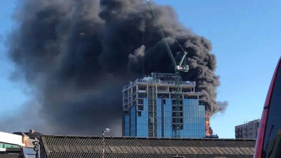 Image of a burning building and a crane next to it.