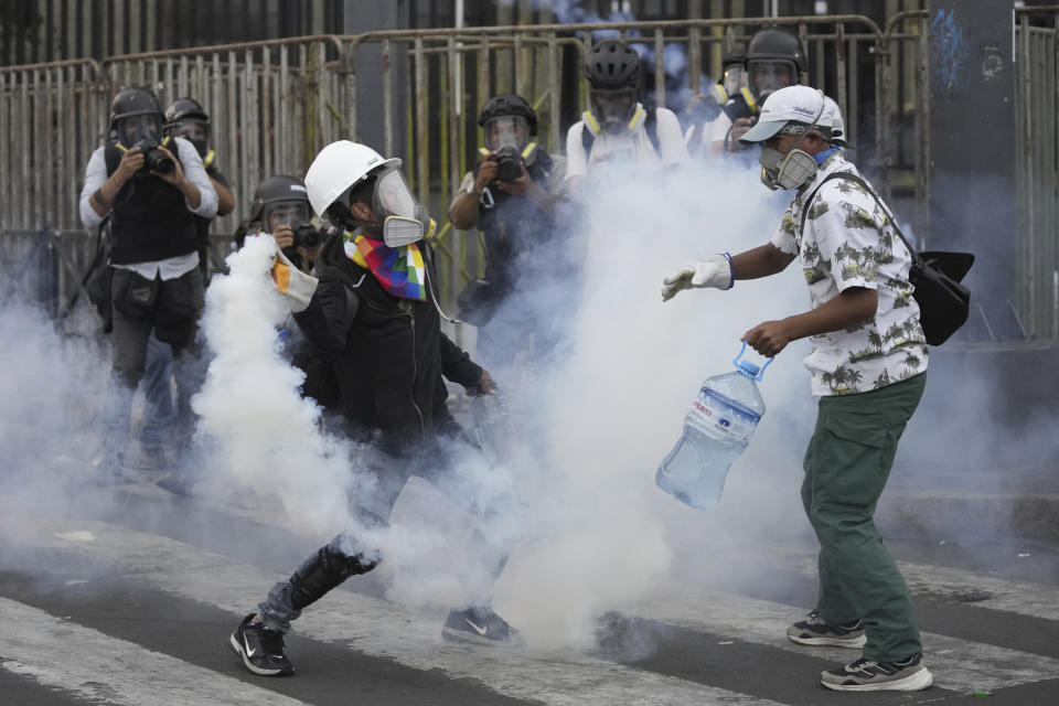 So-called "deactivators" work to neutralize a tear gas canister during an anti-government protest seeking immediate elections, President Dina Boluarte's resignation, the release of ousted President Pedro Castillo and justice for protesters killed in clashes with police, in Lima, Peru, Saturday, Jan. 28, 2023. The protest movement's "deactivators," volunteers donning gas masks, safety goggles and thick gloves, grab the hot tear gas canisters and toss them inside large plastic bottles filled with a mixture of water, baking soda and vinegar, a strategy to try to neutralize the effects of tear gas. (AP Photo/Martin Mejia)