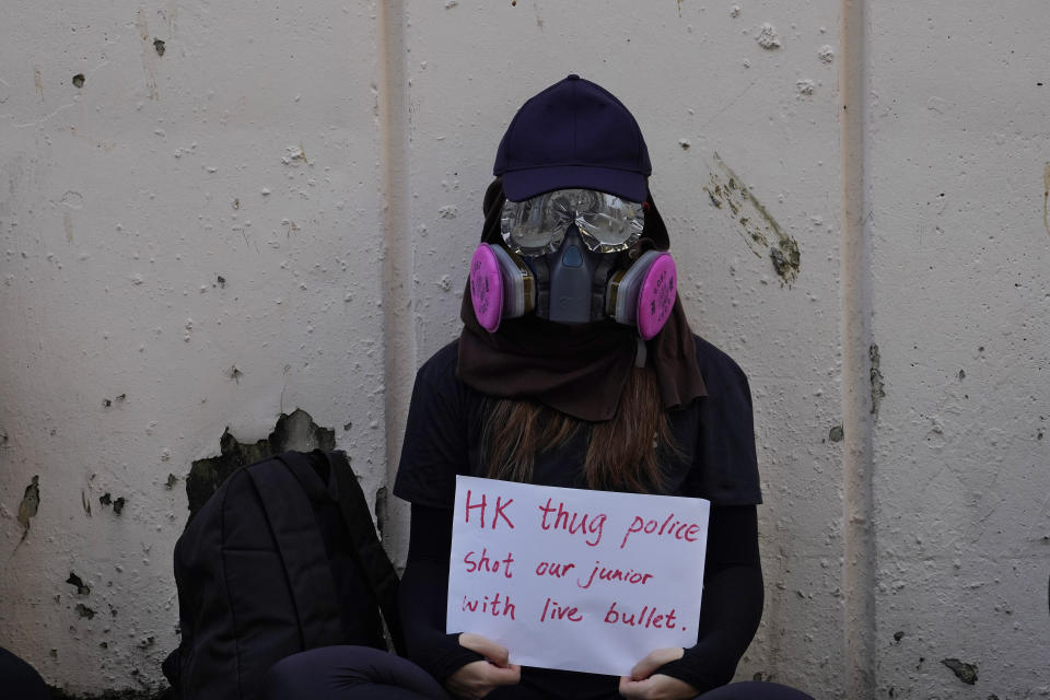 A supporter wearing a gasmask holds a placard during a strike in Hong Kong, Wednesday, Oct. 2, 2019. Hundreds of students at a Hong Kong college have staged a strike to condemn police shooting of a teenager during widespread violence in the semi-autonomous Chinese territory at pre-democracy protests that marred China's National Day. (AP Photo/Vincent Yu)