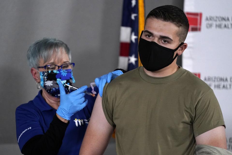 Arizona Air National Guard medic Will Smith, right, receives one of the first doses of the Pfizer-BioNTech vaccine for COVID-19 at the Arizona Department of Health Services State Laboratory from nurse Machrina Leach, Wednesday, Dec. 16, 2020, in Phoenix. The Pfizer vaccine was almost 95 percent effective at preventing patients from contracting COVID-19 and caused no major side effects in a trial of nearly 44,000 people. (AP Photo/Ross D. Franklin)