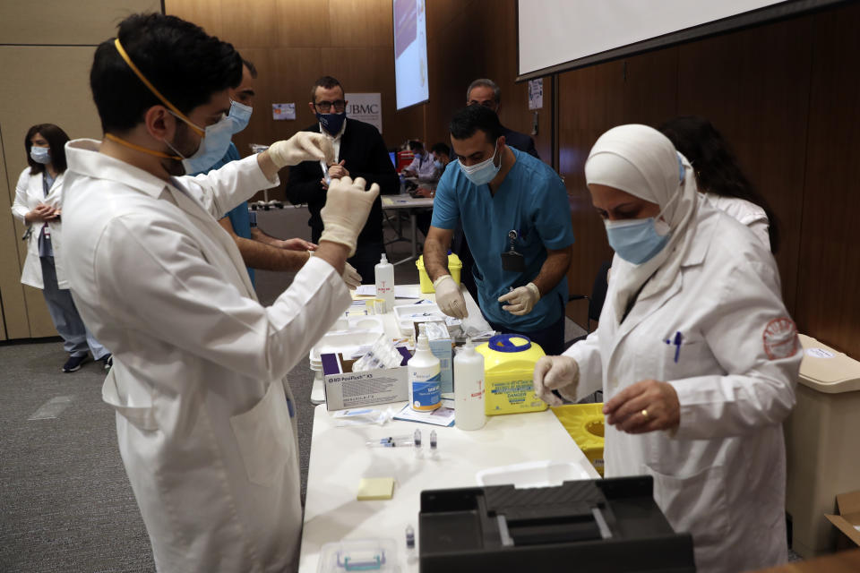 Medical works prepare the syringes of the Pfizer-BioNTech COVID-19 vaccine during a nationwide vaccination program at the American University Medical Center in Beirut, Lebanon, Sunday, Feb. 14, 2021. (AP Photo / Bilal Hussein)