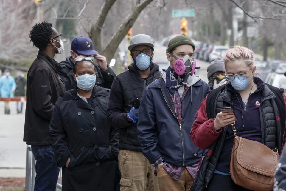 FILE - In this April 7, 2020, file photo, voters masked against coronavirus line up Wisconsin's primary election in Milwaukee. Wisconsin Gov. Tony Evers has issued a new statewide mask order an hour after the Republican-controlled Legislature voted to repeal his previous mandate on Thursday, Feb. 4, 2021. The Democrat Evers said in a video message Thursday that his priority is keeping people safe and that wearing a mask was the most basic way to do that. (AP Photo/Morry Gash, File)