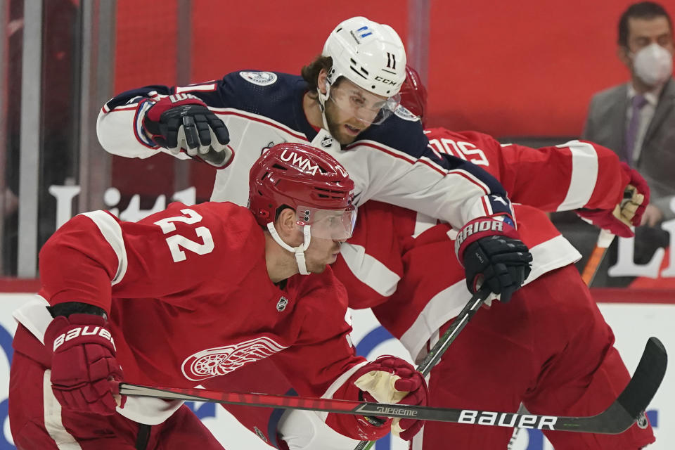 Columbus Blue Jackets center Kevin Stenlund (11) is squeezed in by Detroit Red Wings defensemen Patrik Nemeth (22) and Christian Djoos during the first period of an NHL hockey game, Saturday, March 27, 2021, in Detroit. (AP Photo/Carlos Osorio)