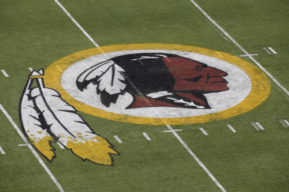 FILE - In this Aug. 7, 2014 file photo, the Washington Redskins NFL football team logo is seen on the field before an NFL football preseason game against the New England Patriots in Landover, Md. The recent national conversation about racism has renewed calls for the Washington Redskins to change their name. D.C. mayor Muriel Bowser called the name an "obstacle" to the team building its stadium and headquarters in the District, but owner Dan Snyder over the years has shown no indications he'd consider it. (AP Photo/Alex Brandon, File)
