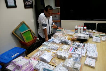 An officer from the National Police Criminal Investigation department looks at evidence confiscated from raids linked to fake vaccines production and distribution in a crackdown carried out in the capital Jakarta and neighbouring Banten and West Java Provinces, at national police headquarters in Jakarta, Indonesia June 27, 2016. REUTERS/Darren Whiteside