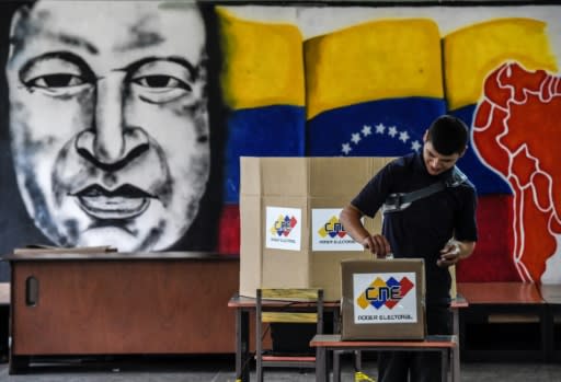 A man votes in front of an image of late Venezuelan president Hugo Chavez