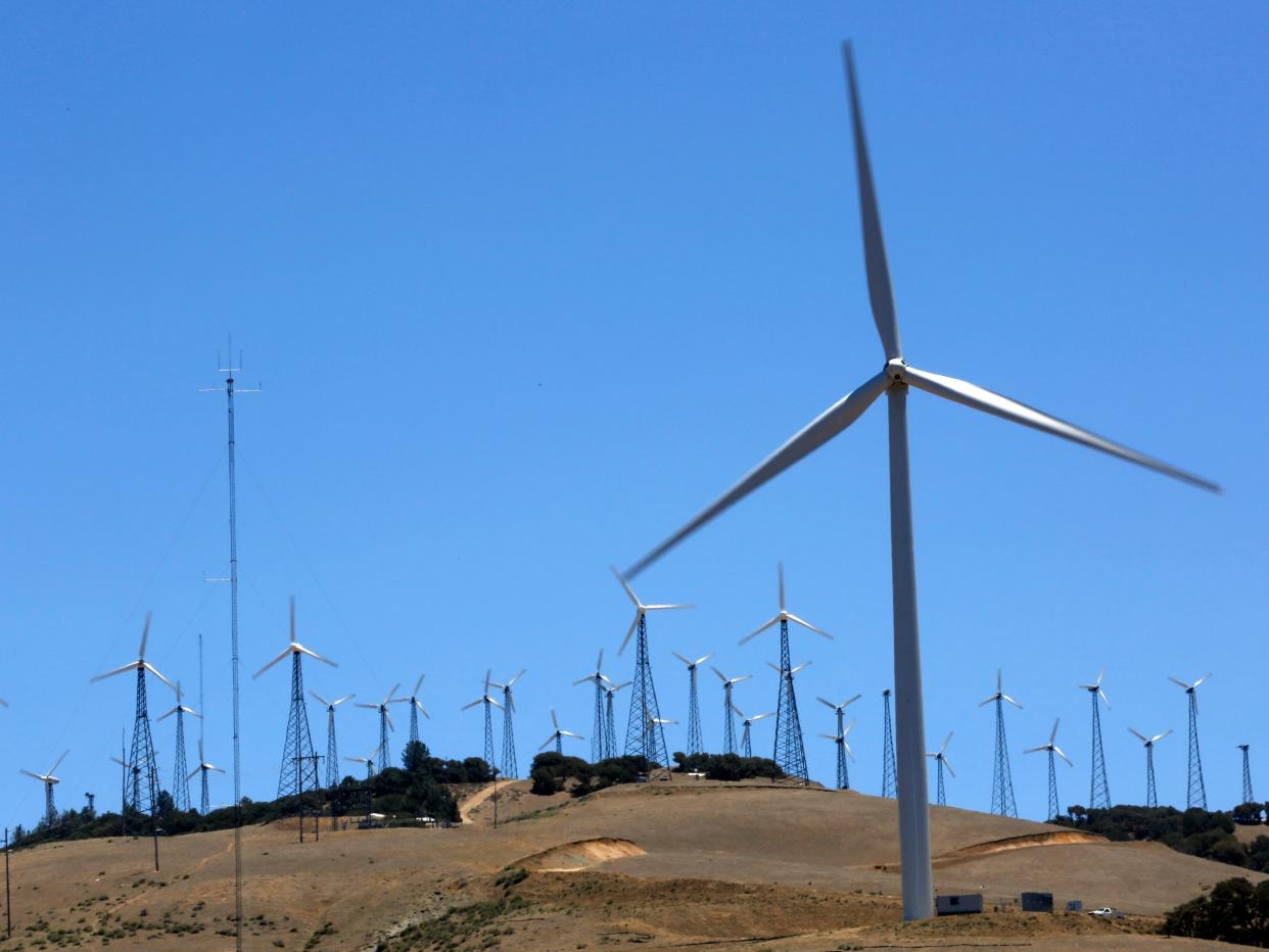 Several wind turbines are seen on a hillside.