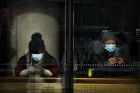 People wearing face masks to protect against the coronavirus sit in a coffee shop in Beijing, Saturday, Nov. 28, 2020. (AP Photo/Mark Schiefelbein)