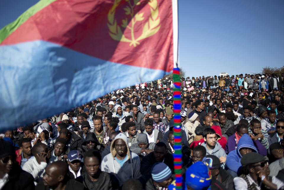 An African migrants holds an Eritrean flag during a protest outside Israel’s parliament in Jerusalem, Wednesday, Jan. 8, 2014. Thousands of African migrants demanded to be recognized as refugees in a protest Wednesday outside of Israel’s parliament, part of a series of events showing the migrants’ growing frustration with their fate in Israel. Police said more than 10,000 migrants rallied outside the Knesset, with hundreds more continuing to stream in to Jerusalem from around the country. The migrants have staged two other mass protests in Tel Aviv where they have demanded the right to work and better treatment from the Israeli government. (AP Photo/Ariel Schalit)