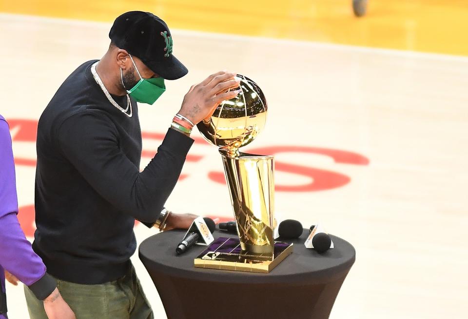 Lakers star LeBron James places his hand on the Larry O'Brien Trophy.