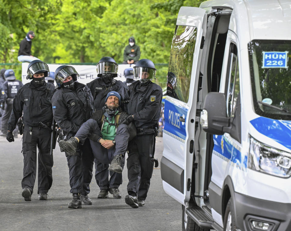 Police carry a activist from a blocade, at the access road to Neuhardenberg airfield, in Neuhardenberg, Germany, Friday, May 10, 2024. Tesla vehicles produced at the Gr'nheide plant are temporarily stored on the airfield site. (Patrick Pleul/dpa via AP)