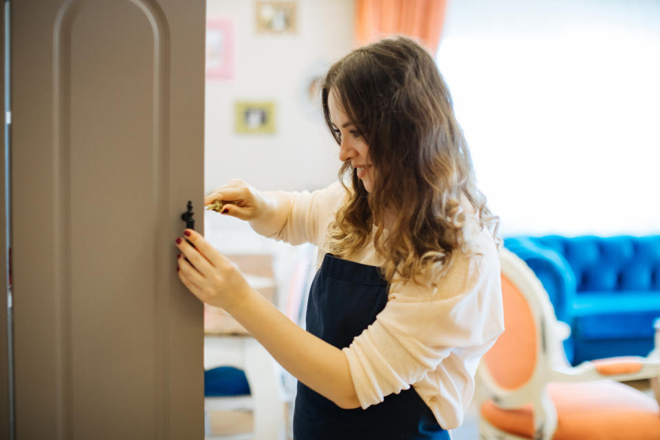 A woman is adding hardware to her cabinets