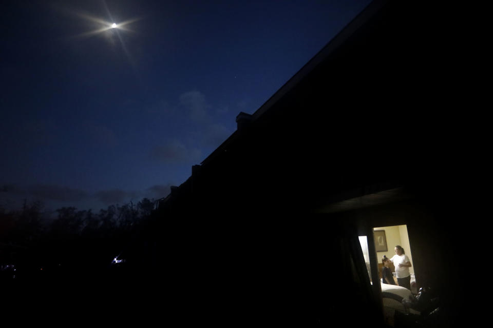 The moon shines above as Nola Davis, right, brushes the hair of granddaughter, Jayden Billingly, 10, before going to bed in their room at the damaged American Quality Lodge where they continue to live in the aftermath of Hurricane Michael, in Panama City, Fla., Tuesday, Oct. 16, 2018. Simply getting through the day is a struggle at the low-rent motel where dozens of people are living in squalor amid destruction left by the hurricane. (AP Photo/David Goldman)