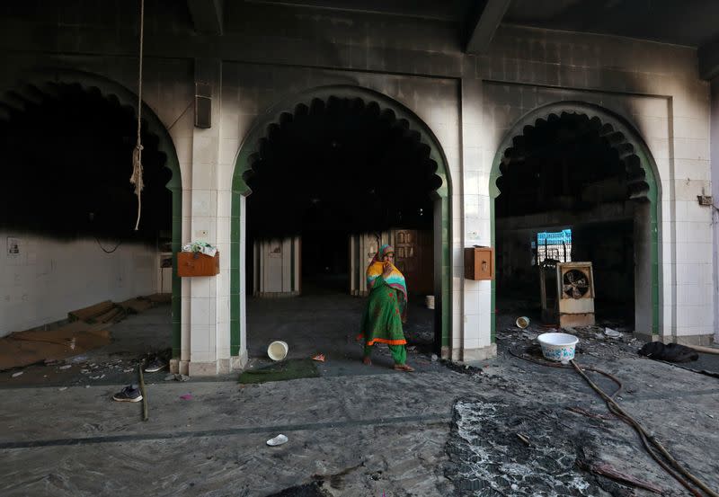 A woman walks inside a partially damaged mosque after it was set on fire by a mob in a riot affected area after clashes erupted between people demonstrating for and against a new citizenship law in New Delhi