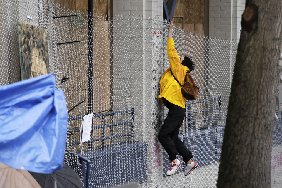 A man leaps to leave a red paint handprint on a plywood-covered and closed Seattle police precinct Tuesday, June 9, 2020, in Seattle, following protests over the death of George Floyd, a black man who died in police custody in Minneapolis. Under pressure from city councilors, protesters and dozens of other elected leaders who have demanded that officers dial back their tactics, the police department on Monday removed barricades near its East Precinct building in the Capitol Hill neighborhood, where protesters and riot squads had faced off nightly. Protesters were allowed to march and demonstrate in front of the building, and the night remained peaceful. (AP Photo/Elaine Thompson)