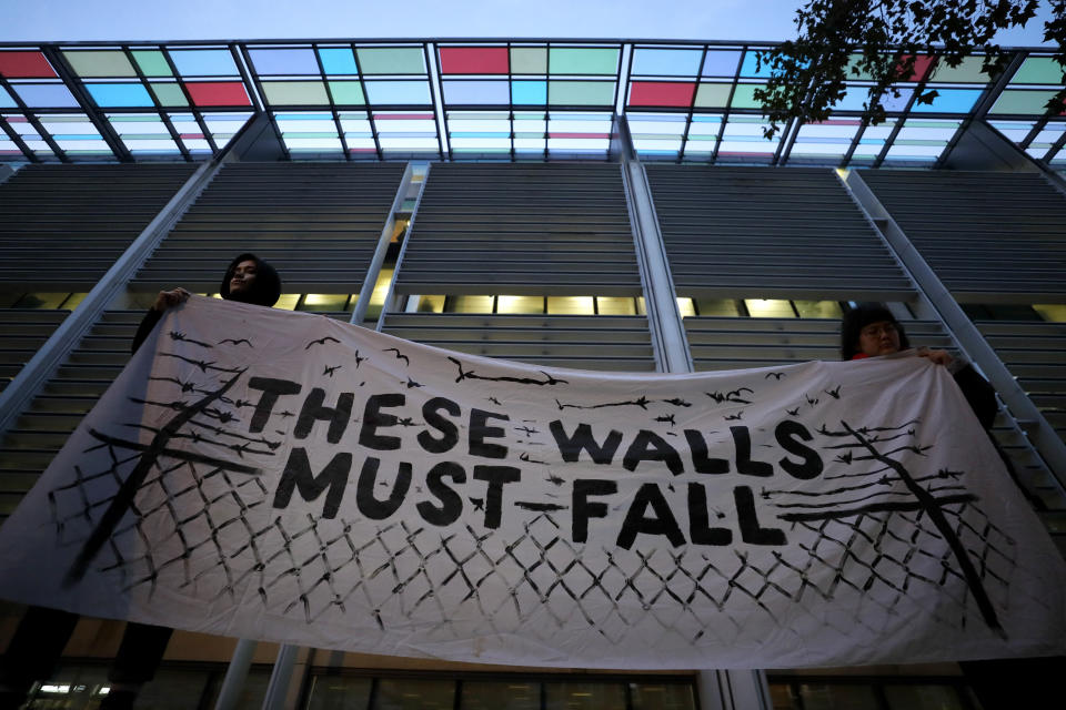 Demonstrators hold a banner during a vigil for the 39 lorry victims, outside the Home Office in London, Thursday, Oct. 24, 2019. Authorities found 39 people dead in a truck in an industrial park in England on Wednesday and arrested the driver on suspicion of murder in one of Britain's worst human-smuggling tragedies. (AP Photo/Kirsty Wigglesworth)