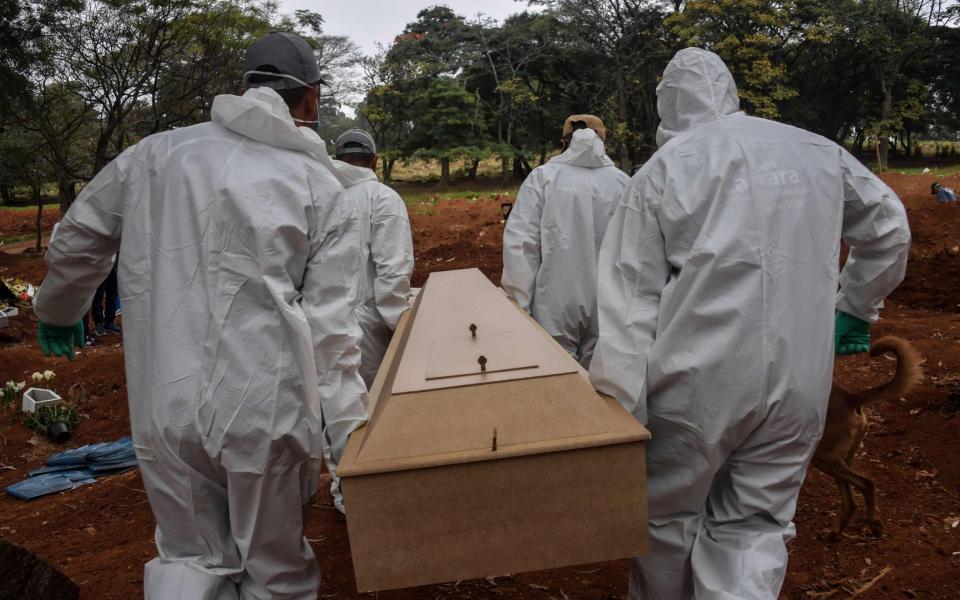 Workers in protective gear carry the coffin of a Covid-19 victim to a grave in Vila Formosa cemetery on the outskirts of Sao Paulo on May 20 - APP