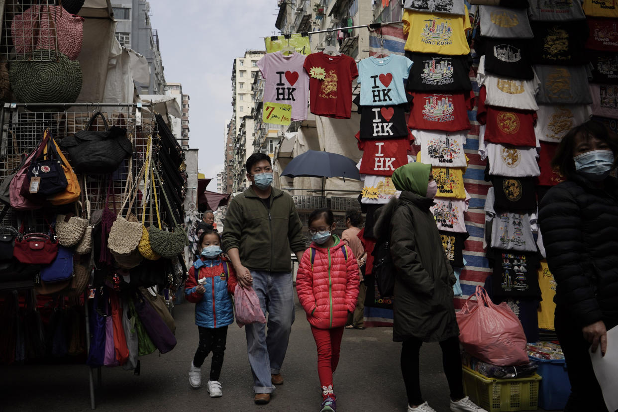 People wear masks at a street where is selling tourist's souvenir in Hong Kong, Saturday, Feb, 1, 2020. China’s death toll from a new virus continues to rise as a World Health Organization official says other governments need to prepare for“domestic outbreak control” if the disease spreads. (AP Photo/Kin Cheung)