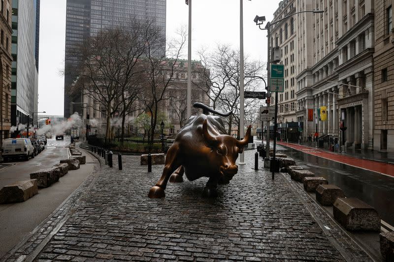 FILE PHOTO: The Wall St. Bull is seen standing on a nearly empty Broadway in the financial district, as the coronavirus disease (COVID-19) outbreak continues, in New York