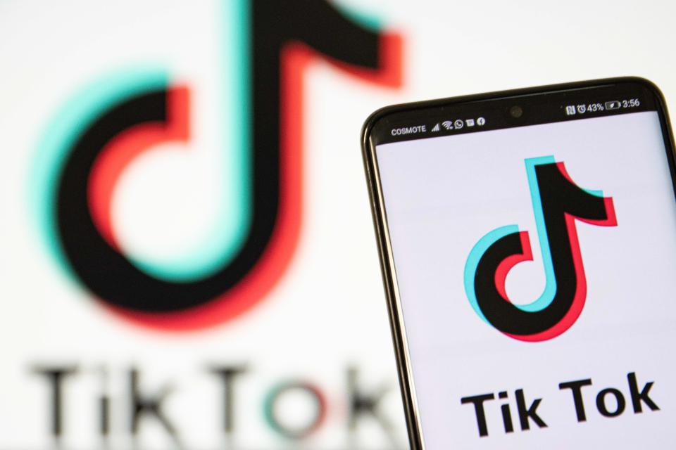 TikTok closeup logo displayed on a phone screen, smartphone and keyboard are seen in this multiple exposure illustration. 