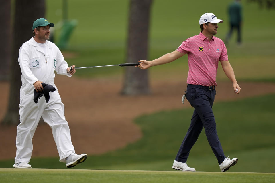 Bernd Wiesberger, of Austria, hands his putter to his caddie Jamie Lane after a birdie on the 15th hole during the second round of the Masters golf tournament on Friday, April 9, 2021, in Augusta, Ga. (AP Photo/David J. Phillip)