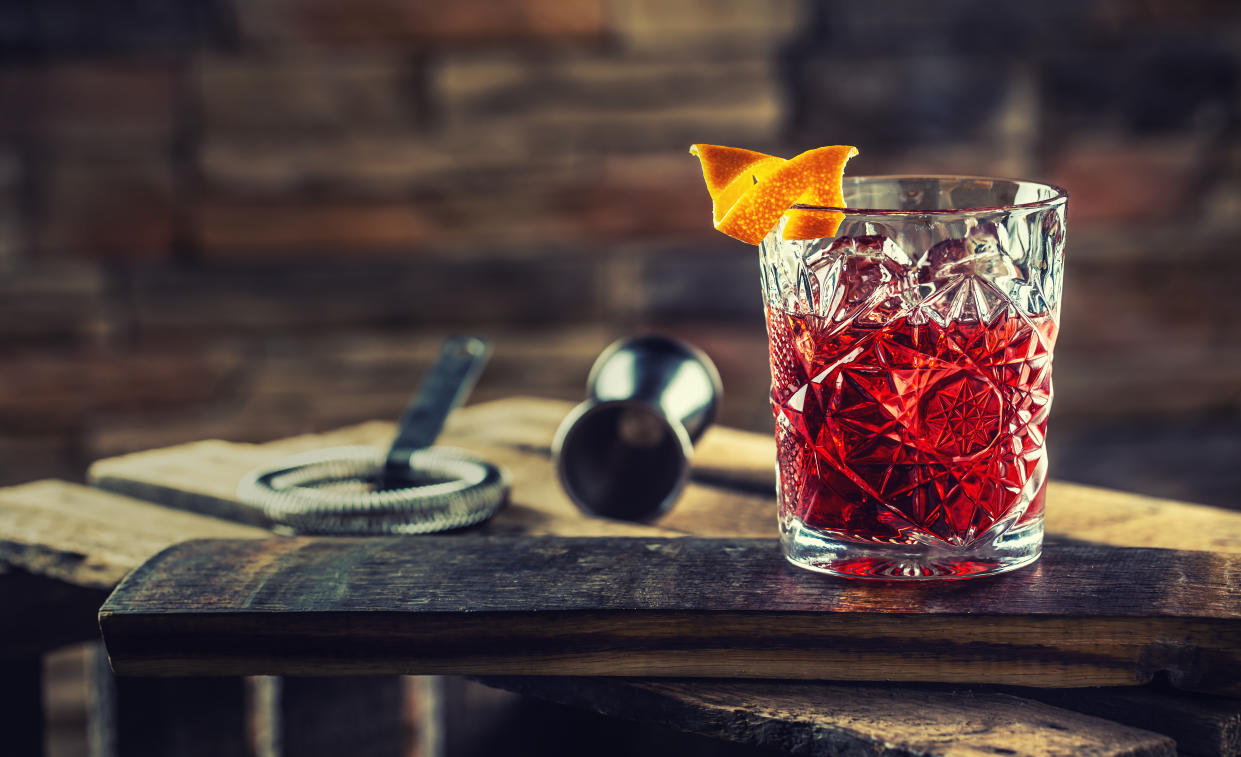 Cocktail Negroni on a old  wooden board. Drink with gin, campari martini rosso and orange.