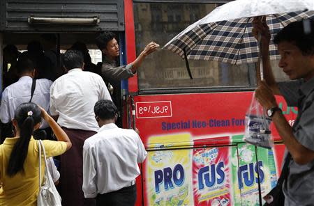 A driver assistant (C) calls out to passengers at a bus stop in Yangon, July 4, 2013. REUTERS/Soe Zeya Tun