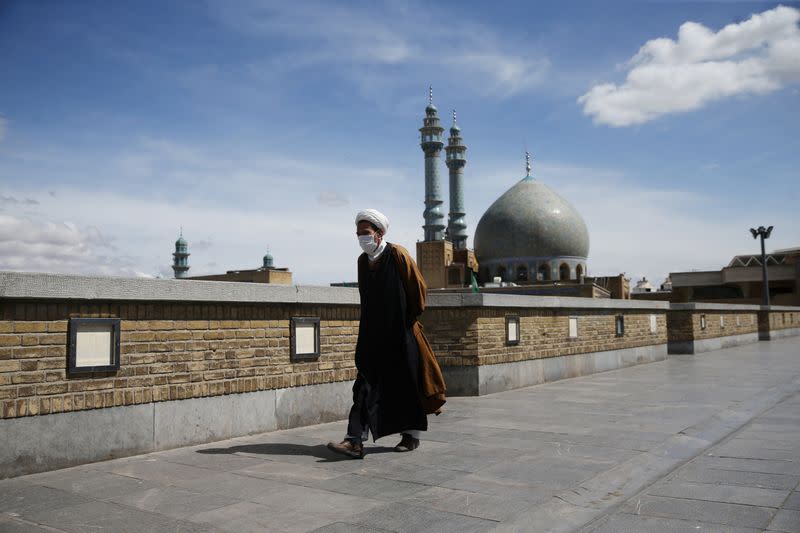 A cleric wearing a protective face mask, following the outbreak of coronavirus disease (COVID-19), walks on the street in Qom