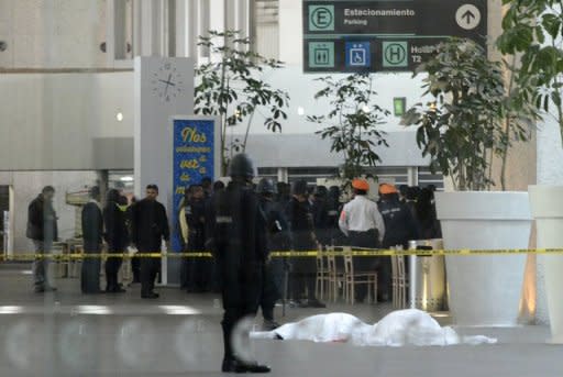 Federal police stand guard next to the bodies of two police officers shot dead in the fast-food area of Benito Juarez international airport Terminal 2, in Mexico City, on June 25, 2012