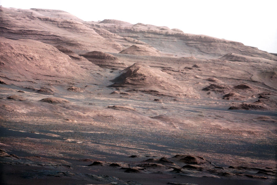 <p>The base of Mars’s Mount Sharp — the rover’s eventual science destination — is pictured in this NASA handout photo taken by the Curiosity rover. The image is a portion of a larger image taken by Curiosity’s 100-millimeter Mast Camera on Aug. 23, 2012. Scientists enhanced the color to show the Martian scene under the lighting conditions we have on Earth, which helps in analyzing the terrain. (Photo: NASA/Reuters) </p>