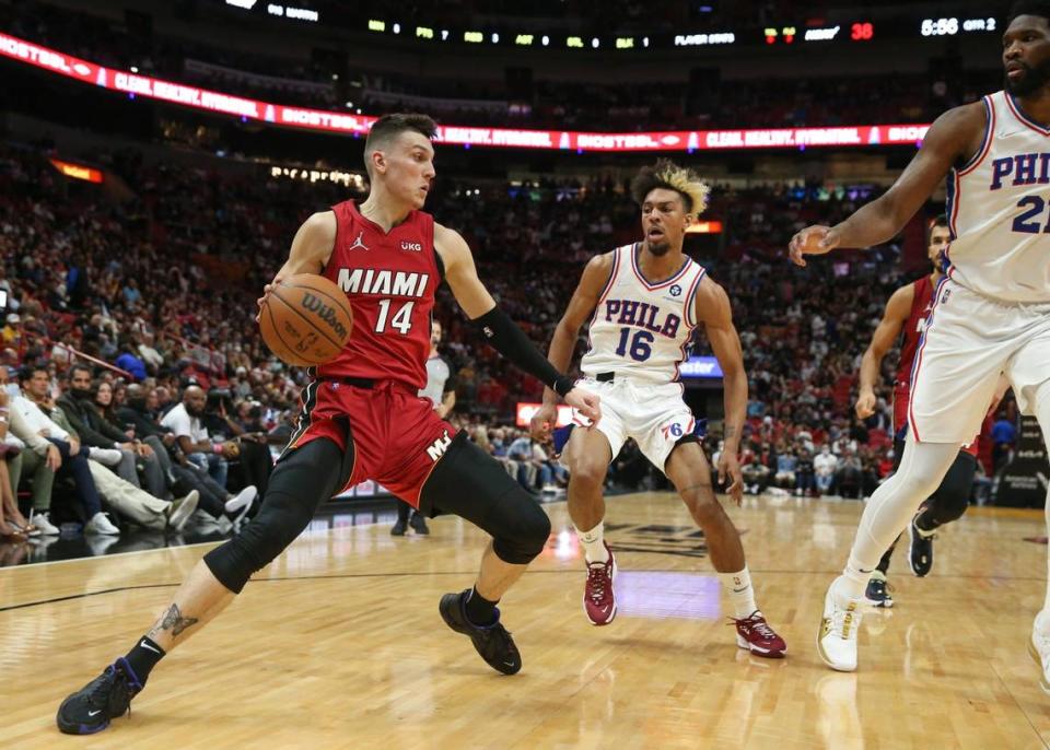Miami Heat guard Tyler Herro (14) drives the ball as Philadelphia 76ers guard Charlie Brown Jr. (16) and center Joel Embiid (21) defend in the first half at FTX Arena in Miami on Saturday, January 15, 2022.