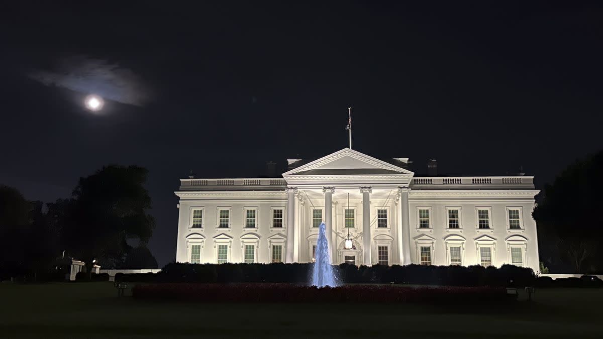 A large white building is shown at night, with the moon visible on its left. A fountain is in front of the building. Anadolu Agency/Contributor, Getty Images