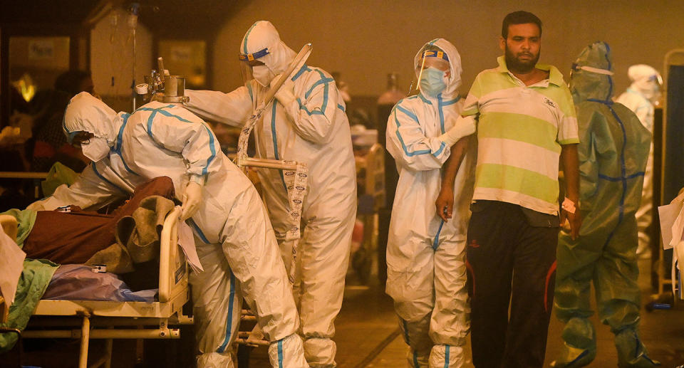 Health workers wearing personal protective equipment (PPE kit) attends to Covid-19 coronavirus positive patients inside a banquet hall temporarily converted into a covid care centre in New Delhi on April 28, 2021. (Photo by Prakash SINGH / AFP) (Photo by PRAKASH SINGH/AFP via Getty Images)