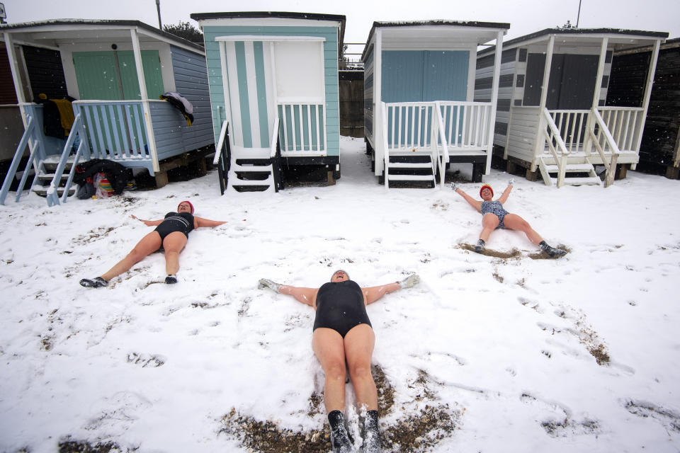 Swimmers (left to right) Sallyann Manthorp, Peta Hunter and Victoria Carlin make snow angels on the beach after swimming in the 1.4 degree water at Thorpe Bay, Essex, as bitterly cold winds continue to grip much of the nation. Picture date: Tuesday February 9, 2021.