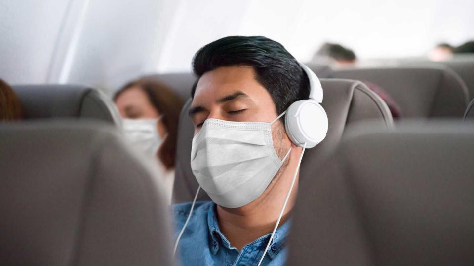 Man traveling and sleeping on the plane wearing a facemask