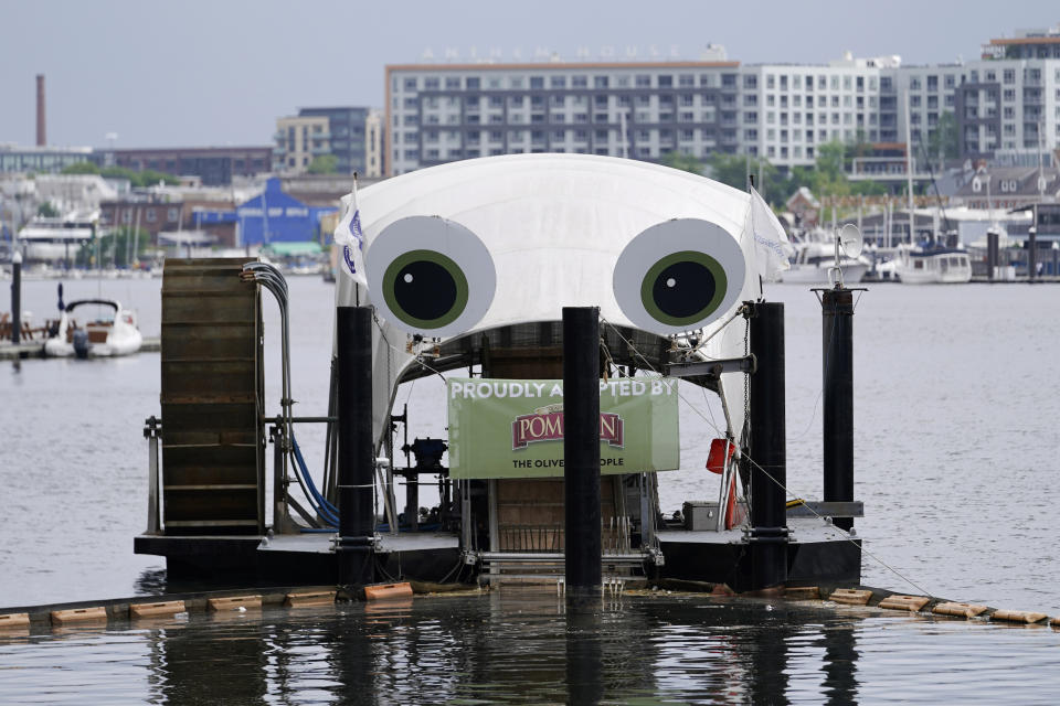 Mr. Trash Wheel, a mechanism that collects trash from tributaries that feed into Baltimore's Inner Harbor sits in the water, Friday, May 13, 2022, in Baltimore. Many novel devices are being used or tested worldwide to trap plastic trash in rivers and smaller streams before it can get into the ocean. Officials say Mr. Trash Wheel has inspired fans to begin recycling or join trash cleanups. (AP Photo/Julio Cortez)