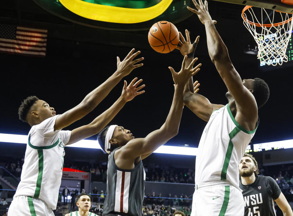 Washington State forward Isaac Jones, center, and Oregon forward Kwame Evans Jr., left, and center N'Faly Dante (1) reach for the ball during the second half of an NCAA college basketball game in Eugene, Ore., Saturday, Feb. 10, 2024. (AP Photo/Thomas Boyd)